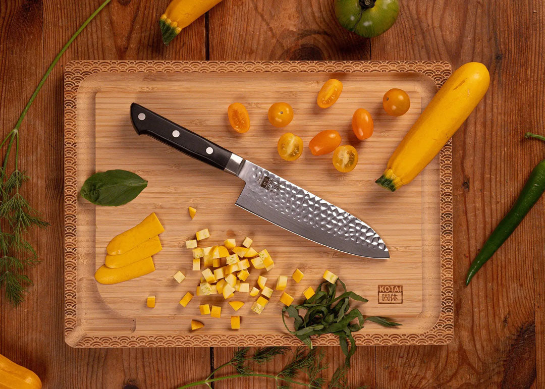 KOTAI Hashi Tsuchime Santoku met 17 cm lemmet op een houten snijplank